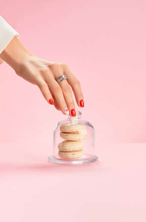 Well-groomed female hand with a ring take macaroon. Trendy fashion accessoriesの写真素材
