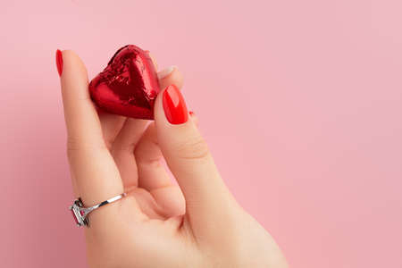Womans hands with red manicure holding candy in heart shape. Valentines dayの写真素材