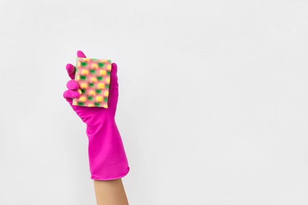 Womans hand in pink rubber glove holding sponge background.の写真素材