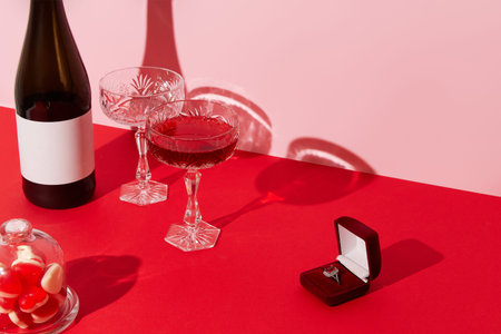 Marriage proposal valentines day concept. Ring, sparkling wine, glasses and candies on red tableの写真素材