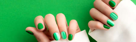 Beautiful groomed womans hands with spring summer nail design on green background.の写真素材