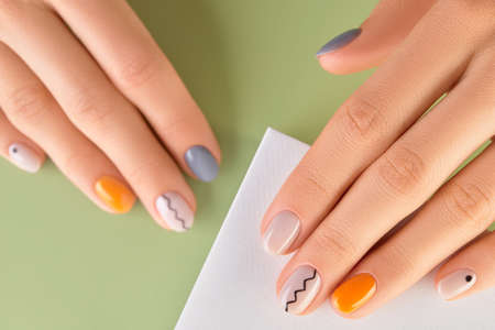 Close up womans hands with trendy minimal manicure on green background. Spring summer nail designの写真素材