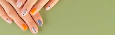 Close up womans hands with trendy minimal manicure on green background. Spring summer nail designの写真素材