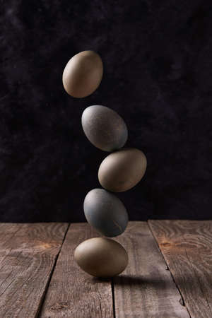 Balancing dyed eggs on wooden table. Easter celebration conceptの写真素材