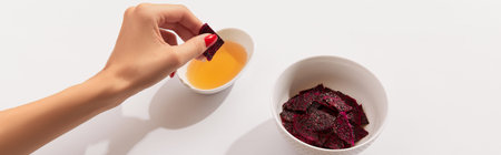 Dried dragon fruit chips and sauce on white background with womans hand