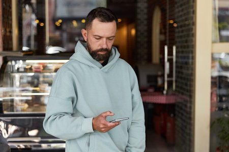 Bearded man in casual clothes using his smartphone