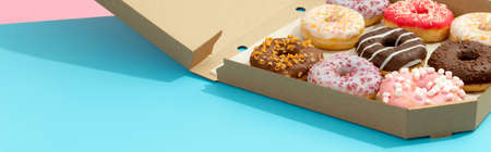 Set of yummy colorful donuts in paper box on blue backgroundの写真素材