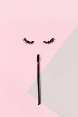 Creative layout with eyelashes and brush mascara. Closed eyes on pastel pink background.の写真素材