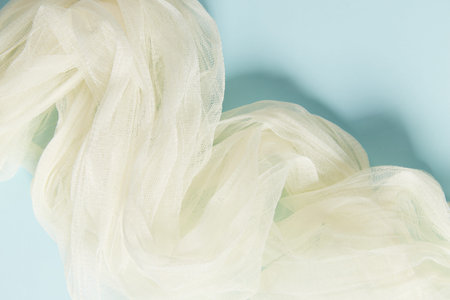 Yellow silk soft fabric on blue background. Elegant and delicate wallpaper