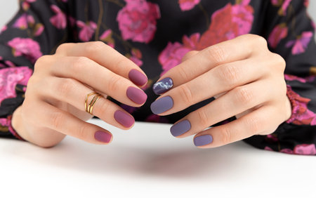 Beautiful womans hands with purple burgundy matte manicure