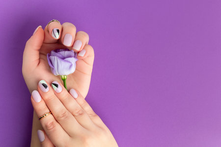 Beautiful womans hands with spring summer design on violet background. Manicure, pedicure beauty salon conceptの写真素材