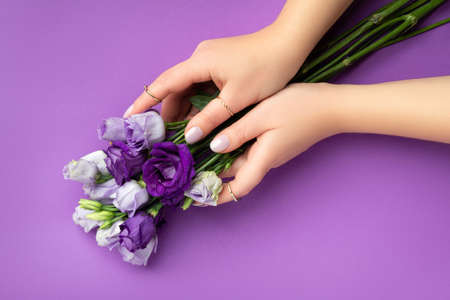Beautiful womans hands with spring summer design on violet background. Manicure, pedicure beauty salon conceptの写真素材