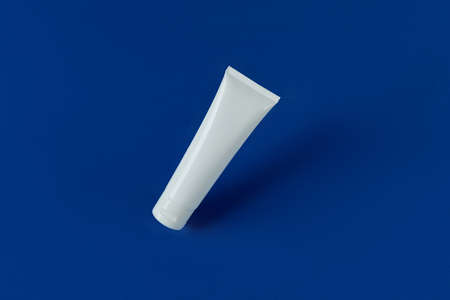 Top view blank white tube bottle with lotion cream or cleanser on blue backgroundの写真素材