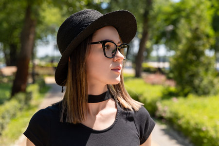 Beautiful woman in black t-shirt and red skirt and glasses walking in the parkの写真素材