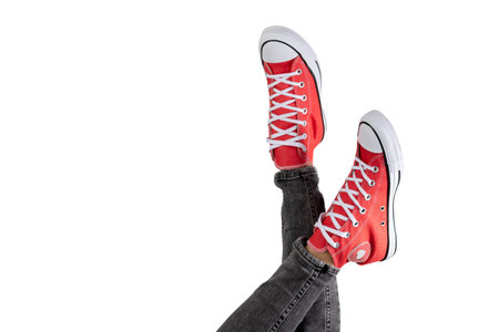 Legs of a young woman in stylish red sneakers on white background.