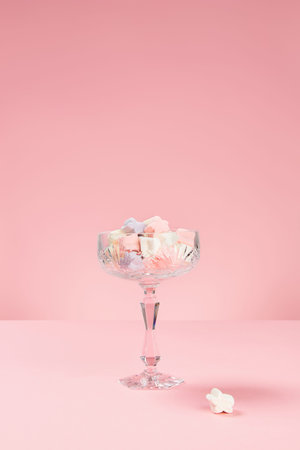 Marshmallows in star shape in a glass on pink background