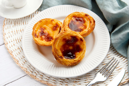 Traditional Portuguese egg tart dessert Pasteis Pastel de nata or Pasteis de Belem on the plate over...