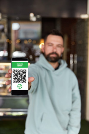 Man showing Qr Code on entrance to the restaurant. Digital vaccination certificate on smartphone....