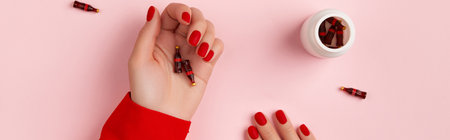 Manicured female hands with tiny bottles of soft drink on pink background. Healthy food dietの写真素材