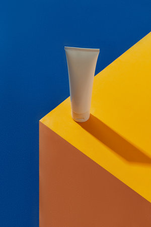 Top view blank white tube bottle with skin care product on blue and orange creative backgroundの写真素材