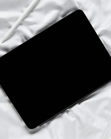 Flat lay top view blank screen digital tablet on white bed. Home office workspace