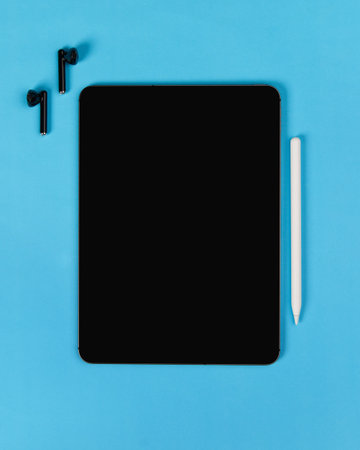 Flat lay top view blank screen digital tablet on blue background. Home office workspace