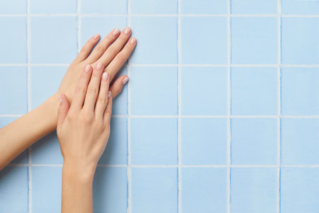 Beautiful womans hands with nude nail design on blue background. Manicure, pedicure beauty salon conceptの写真素材