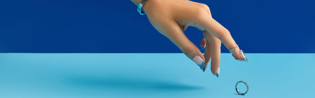 Beautiful manicured womans hand with ring on blue backgroundの写真素材