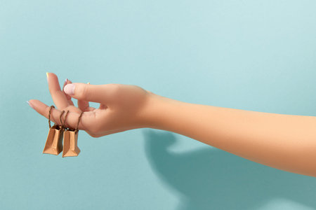 Womans hand with trendy manicure holding tiny paper bagsの写真素材