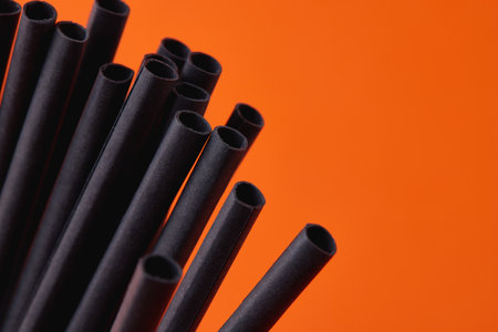 Black paper straws on orange background. Halloween partyの写真素材