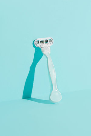 Minimalist elegance: Razor in sharp relief against a bold blue backdrop with dramatic shadows