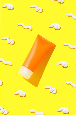 Creative composition with sunscreen lotion on yellow background. Body care beauty treatment concept
