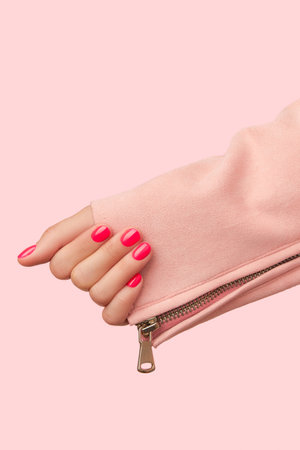 Womans hand with trendy manicure on pastel pink background. Beauty salon concept. Vertical shotの写真素材