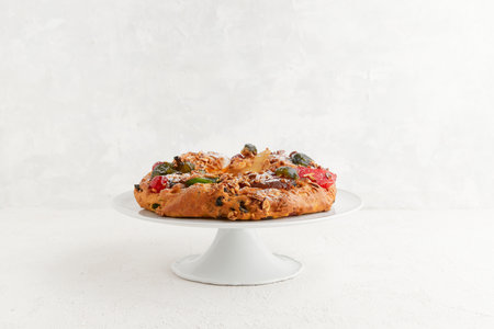 A round festive cake with candied fruit and nuts displayed on a white pedestal standの写真素材