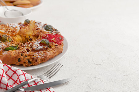 A festive cake with candied fruit and nuts, placed on a white plate with a red and white napkin nearbyの写真素材