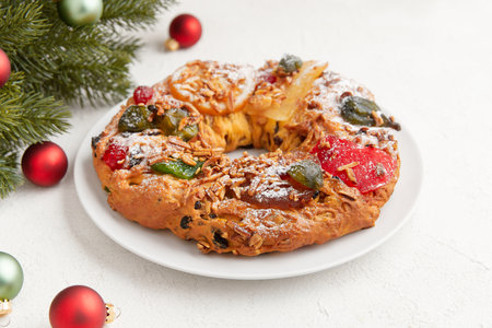 A festive cake adorned with candied fruit and nuts, surrounded by holiday decorations and ornamentsの写真素材