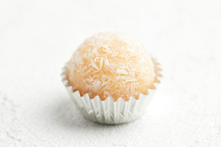 Typical Brazilian sweet brigadeiro. One coconut candy on a white backgroundの写真素材