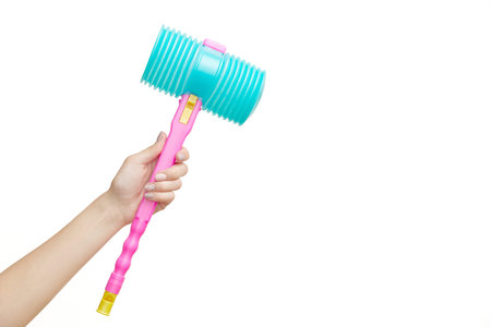 A hand holds up a pink and blue toy hammer against a white background