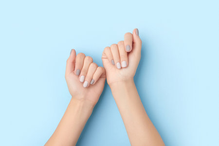 Womans hands with gray nail design on blue backgroundの写真素材