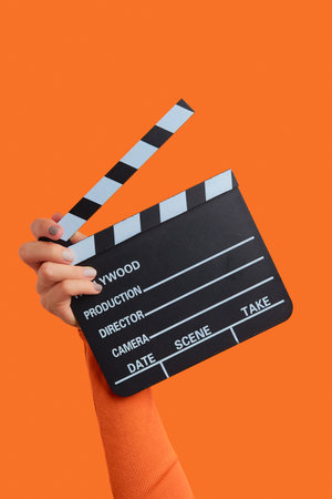 Womans hand holding clapperboard on an orange backgroundの写真素材