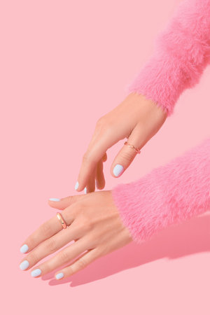 Womans hands with white manicure on pink backgroundの写真素材