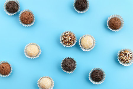 Typical Brazilian sweet brigadeiro. Assorted flavors of candies in a line on a blue backgroundの写真素材