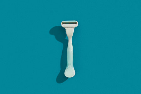 Minimalist elegance: Razor in sharp relief against a bold blue backdrop with dramatic shadowsの写真素材