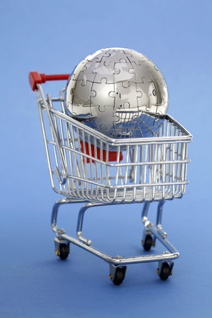 Metal puzzle globe with shopping cart on blue backgroundの写真素材