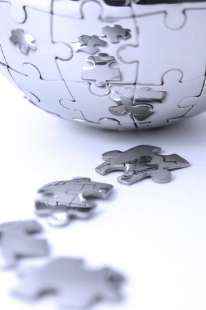 Metal puzzle globe isolated on white background, close-up in blue light の写真素材