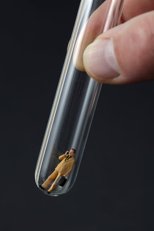 Businessman figurine inside a test tube on black backgroundの写真素材