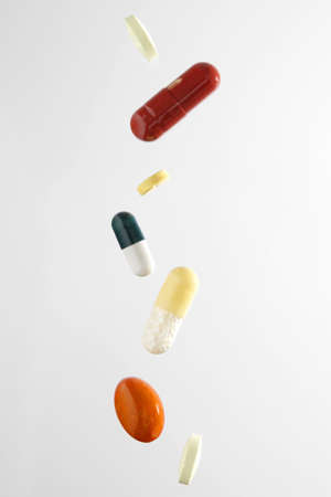 Different medicine pills falling, isolated on white backgroundの写真素材