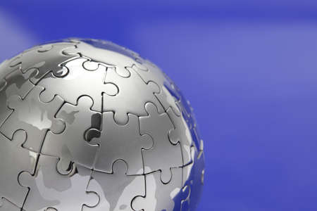 Metal puzzle globe isolated on white background, close-up on blue backgroundの写真素材