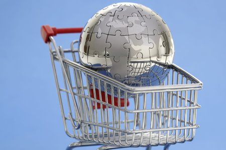 Metal puzzle globe with shopping cart on blue backgroundの写真素材