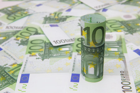 Rolled up 100-Euro bill on Euro background